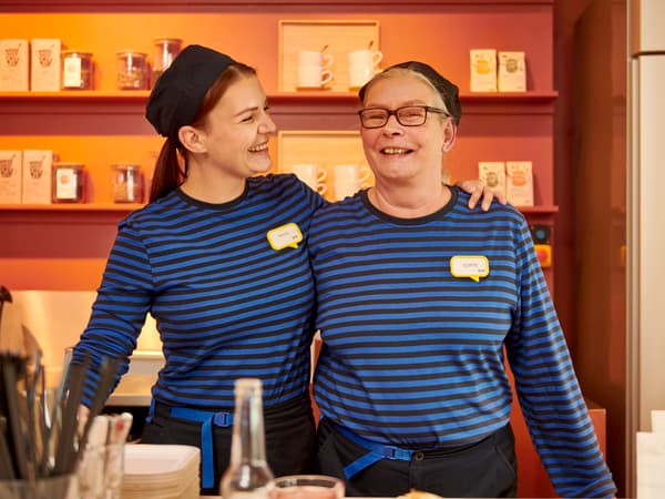 Two IKEA co-workers, dressed in IKEA staff uniforms, smiling