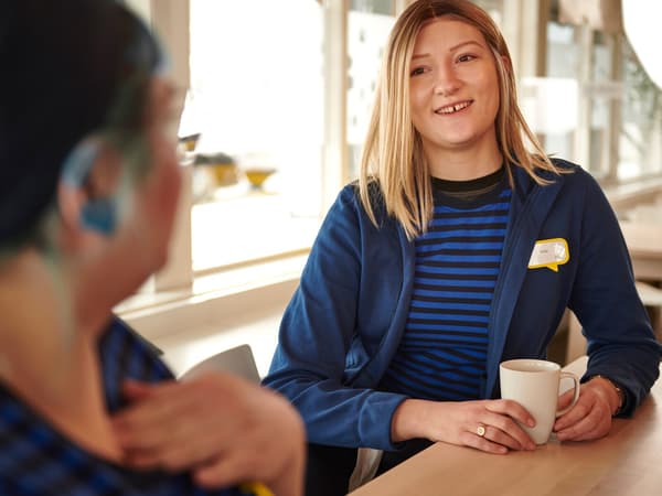 Two IKEA co-workers in blue uniforms enjoying a break in the staff cafe.