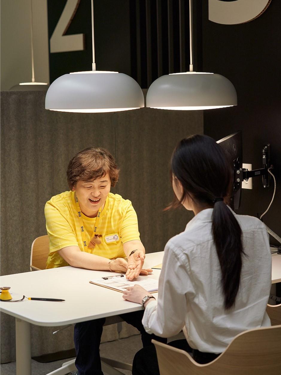 Two IKEA co-workers, one with blue hair, enjoying a glass of water in the staff canteen.
