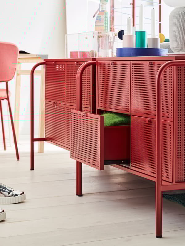 Two IKEA NIKKEBY chest of drawers in red with perforated surfaces, one drawer pulled out revealing green fabric.