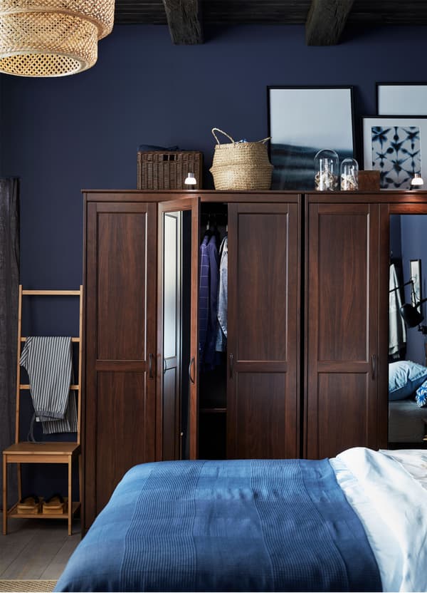 Two IKEA SONGESAND brown wardrobes with mirrored doors, behind a bed with blue and white bedding.