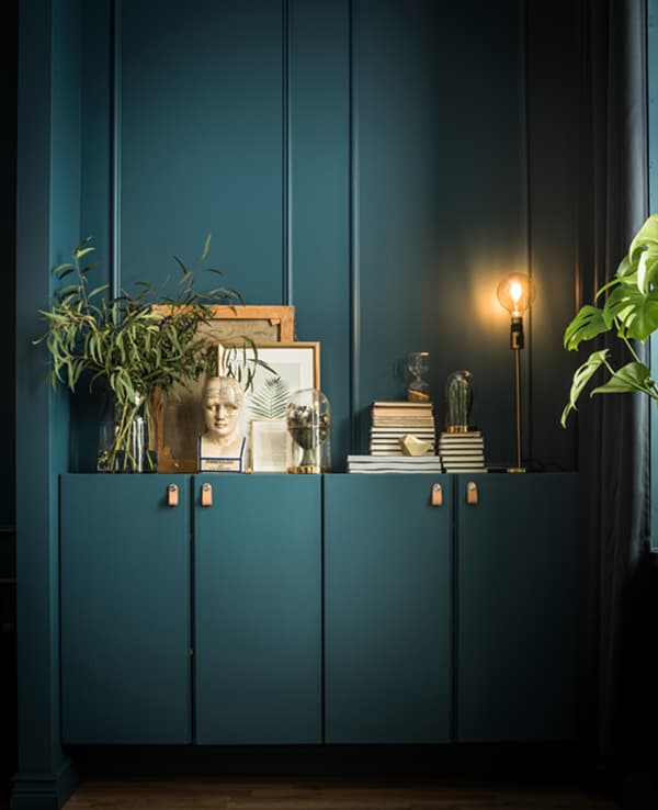 Two IVAR cabinets are custom painted in the same shade as the walls and hold books, artwork, plants, and a lamp on top.