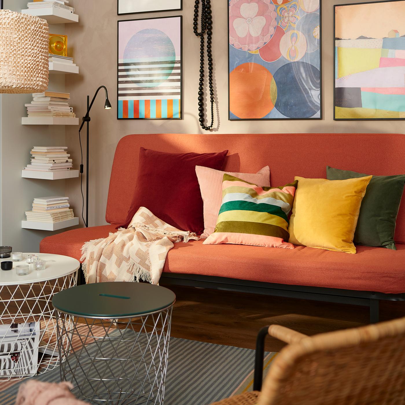 Two KVISTBRO tables in different sizes sit in front of an orange NYHAMN sofa on a stripey rug. A big lamp hangs overhead.
