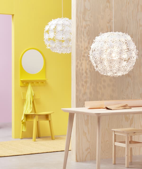 Two large white pendant lamps with floral design hanging in a pink, yellow and light wood room.