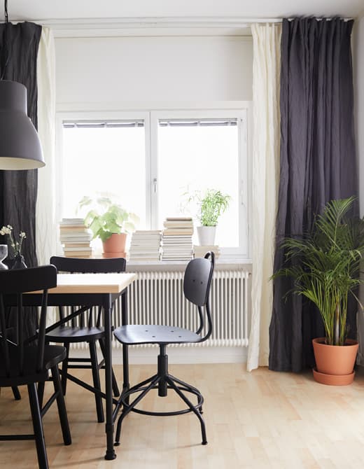 Two layers of white and blue curtains are hung from ceiling to floor and wall to wall in a dining room.