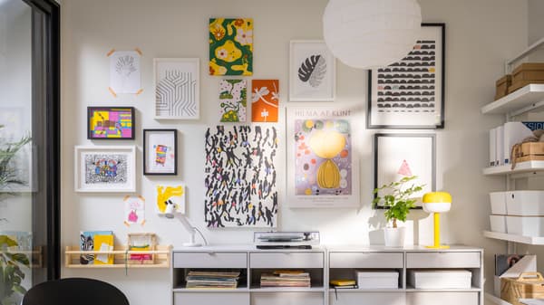 Two light grey SPIKSMED sideboards, one with a record player on top, stand against a wall where many pictures are hung.