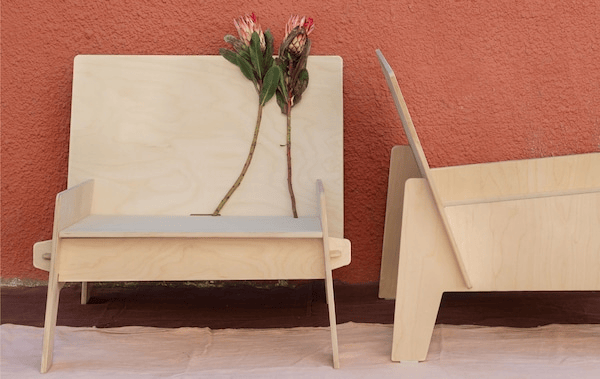 Two low, wide chairs, placed perpendicular from each other, wholly made from fitted, flat sheets of plywood.