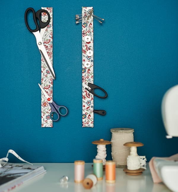 Two magnetic knife racks wrapped in a floral textile hold scissors and sewing tools. 