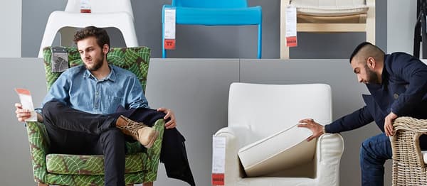 Two men sitting in armchairs at an IKEA store.