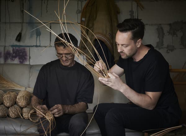 Two men weaving cane in a workshop.