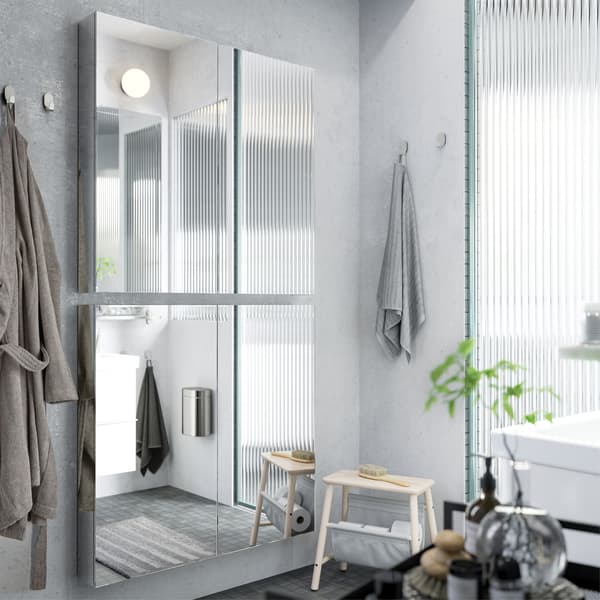 Two mirror cabinets are mounted vertically on a grey bathroom wall to create a full body mirror.