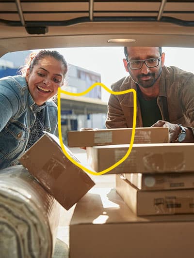 Two people are loading IKEA packages into the boot of a car, shown from the inside of the car