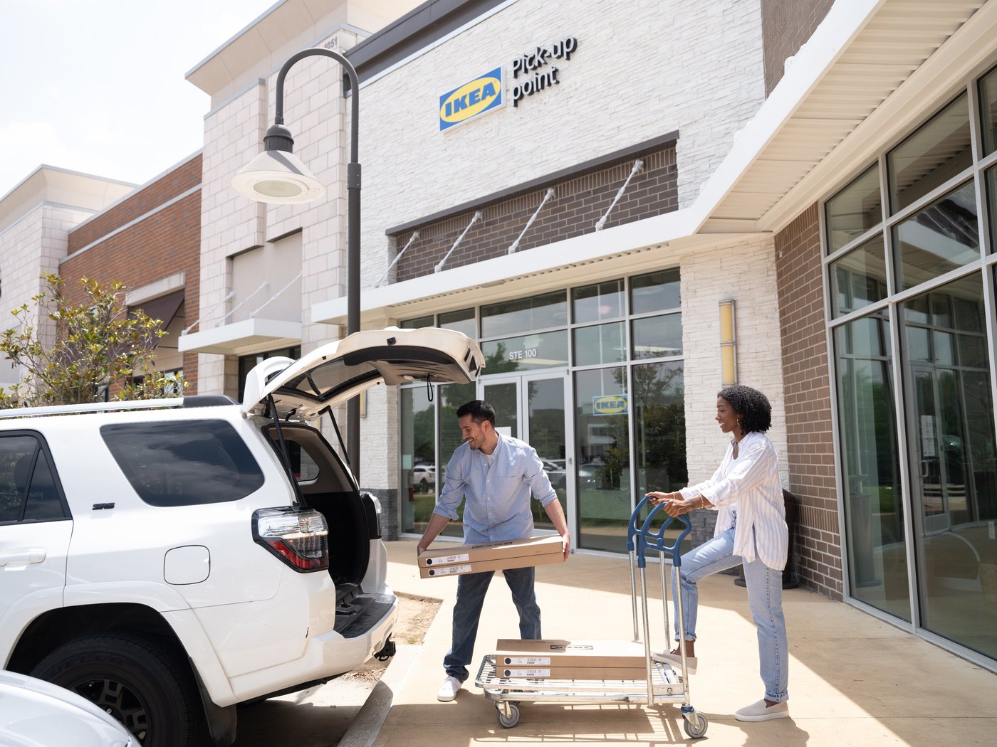 Two people are loading the trunk of a car
