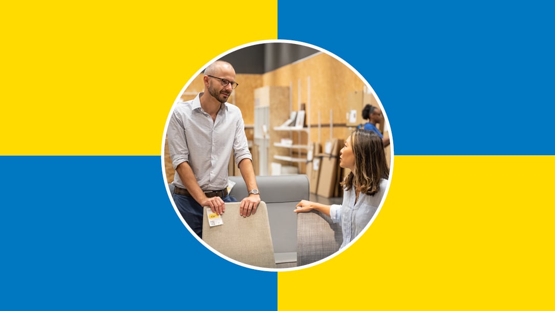 Two people are talking to each other in the As-is section of an IKEA store, with a blue and yellow checkered background