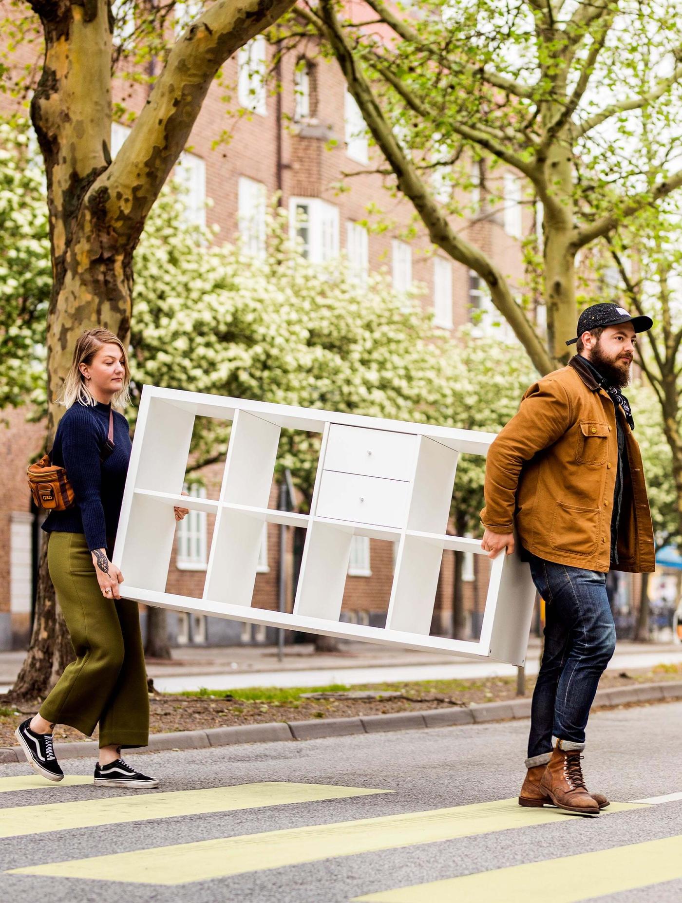 two people carrying KALLAX