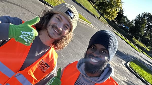 Two people in work jackets and one giving a thumbs up