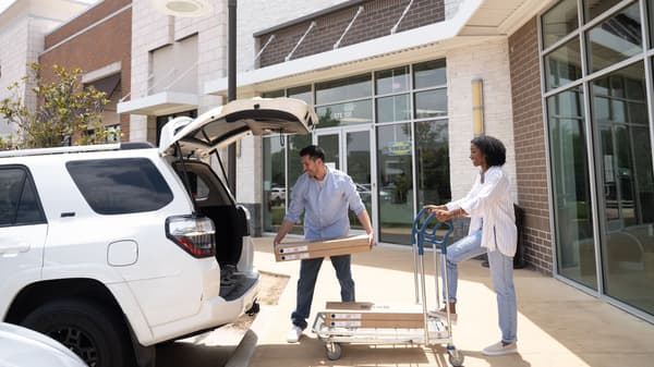 Two people loading IKEA products into the back of  their truck