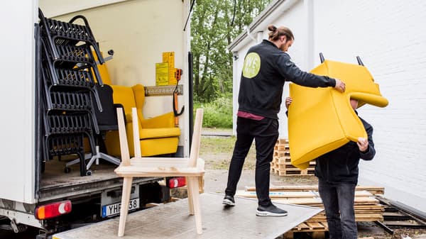 Two people moving furniture out from a car