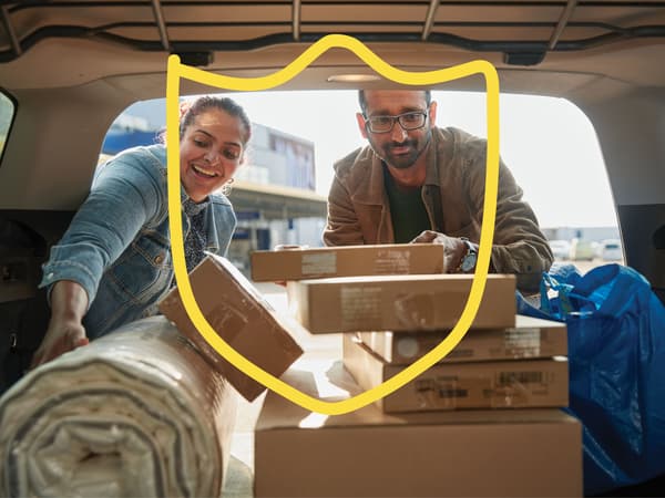 Two people putting IKEA flat-pack boxes in the boot of their car.
