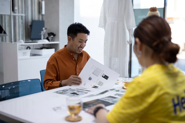 Two people sitting in front of paper designs
