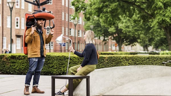 Two people talking to each other holding a chair and a lamp.