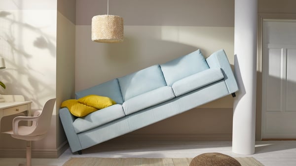 Two people watch a new sofa that didn't fit into the room.