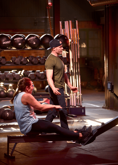 Two people working out in a gym, weights and working out gear in the background.