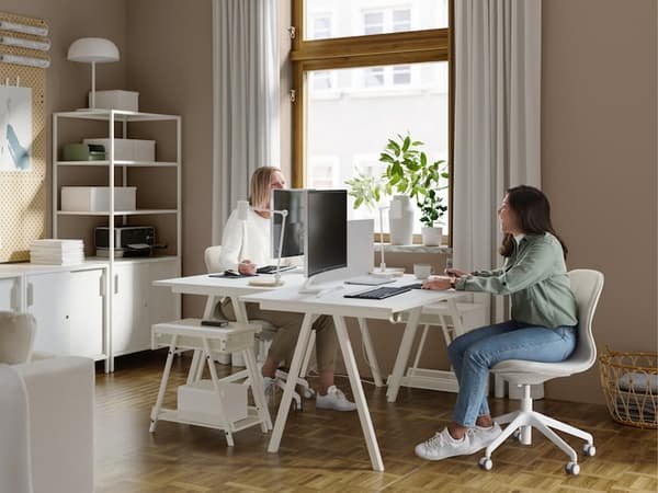 Two persons chatting in an office with white furniture.