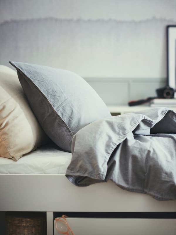 Two pillows and a blanket shown on a bed. 