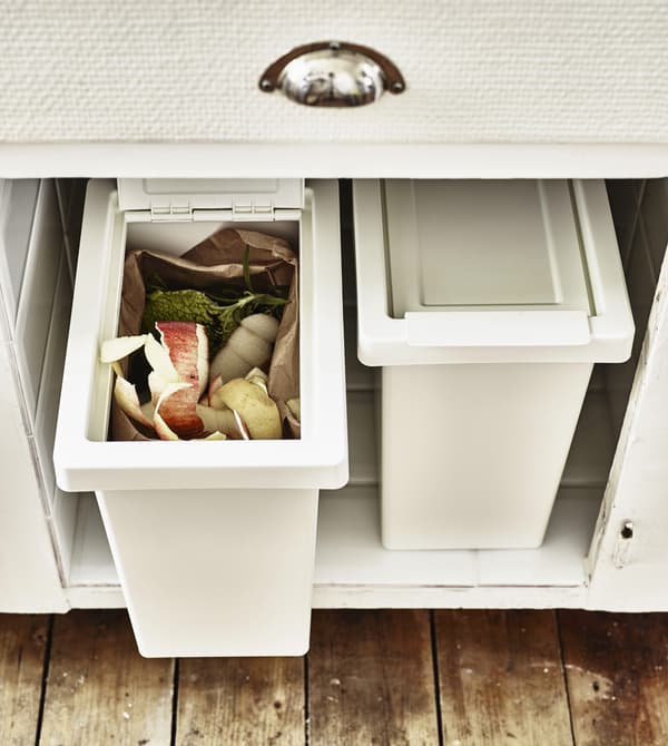 Two recycling boxes inside a kitchen cupboard.