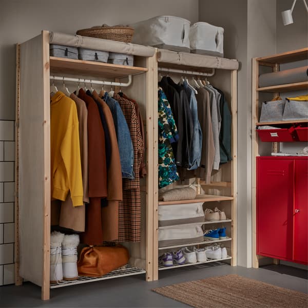 Two shelving units in pine with beige covers that are rolled up. Clothes, shoes and white storage cases are stored inside.