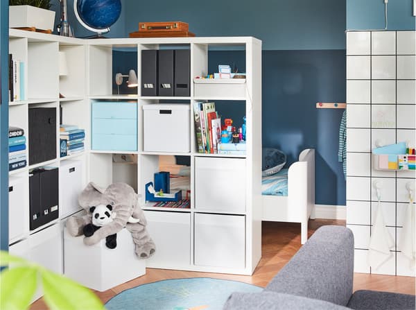 Two shelving units serve as a room divider while offering much storage space. Behind them, you can glimpse a children's bed.