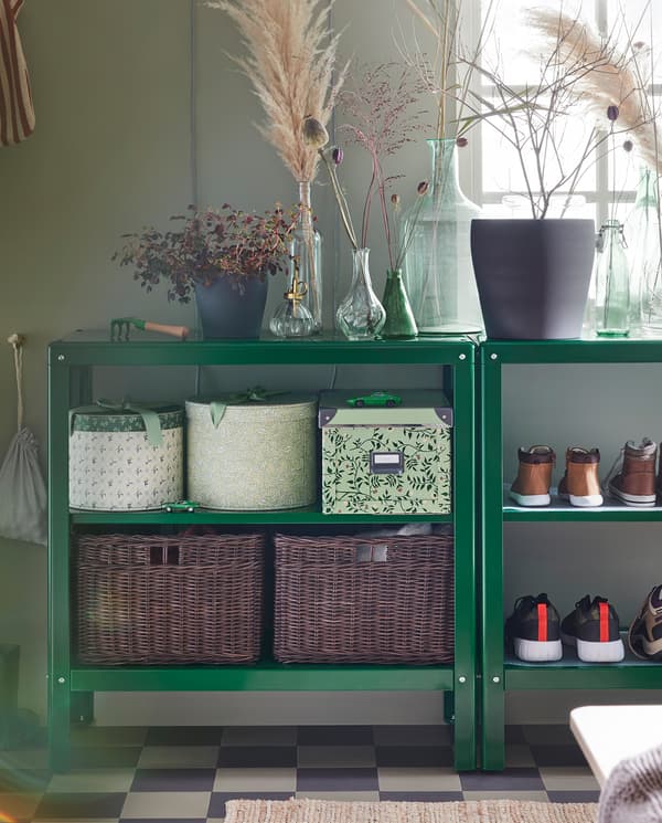 Two shelving units with decorative items on their top shelves and boxes, shoes and baskets in rattan on their lower shelves.