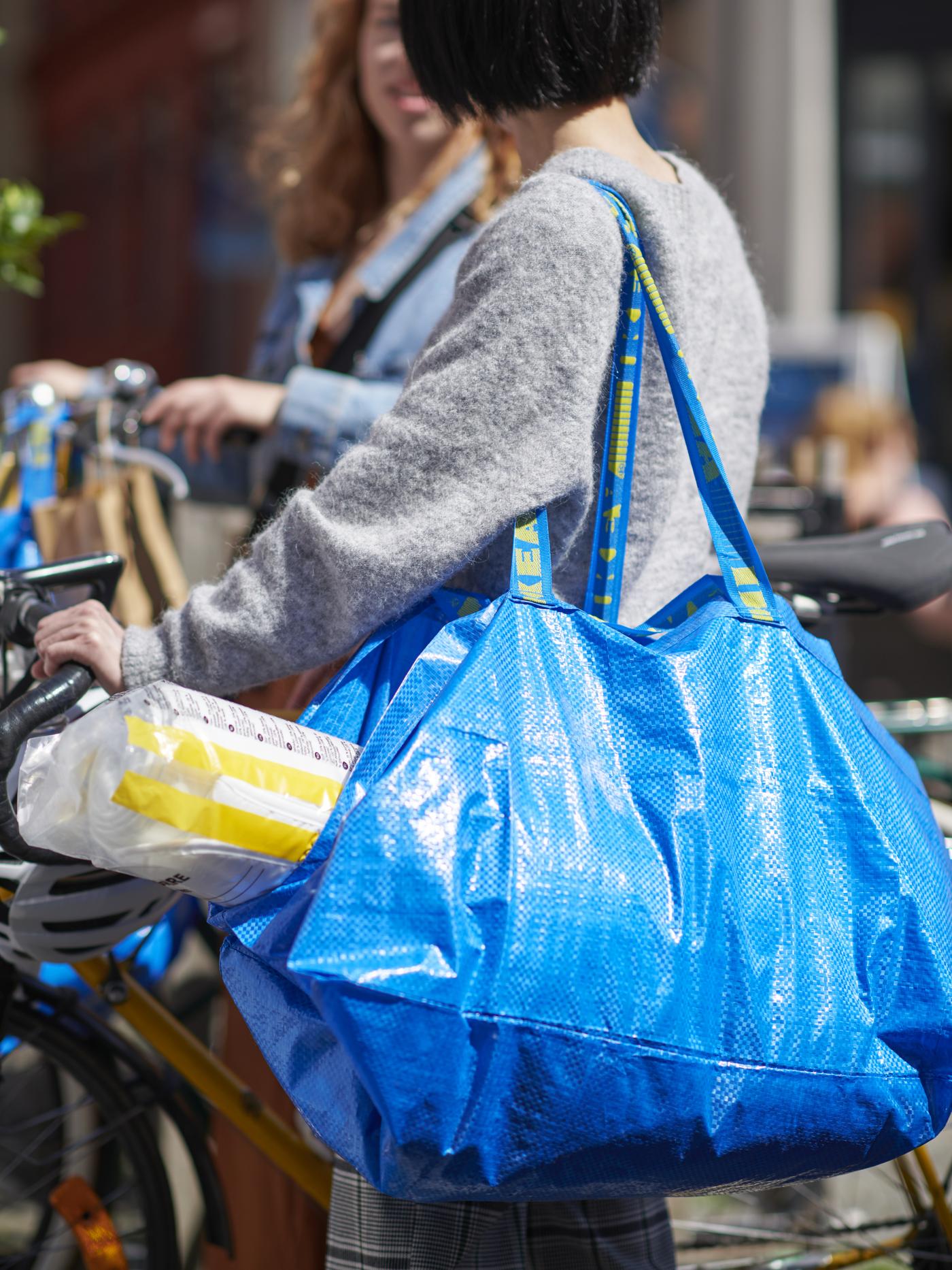 Two shoppers walk home after a shop at IKEA with FRAKTA bags