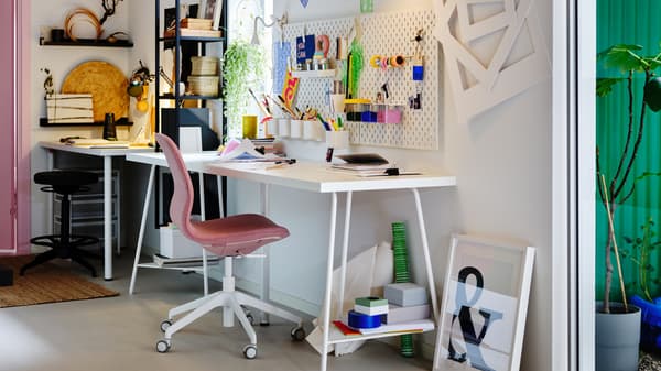 Two side-by-side workspaces, one of them centred around a white LAGKAPTEN table and a brown-pink LÅNGFJÄLL conference chair.