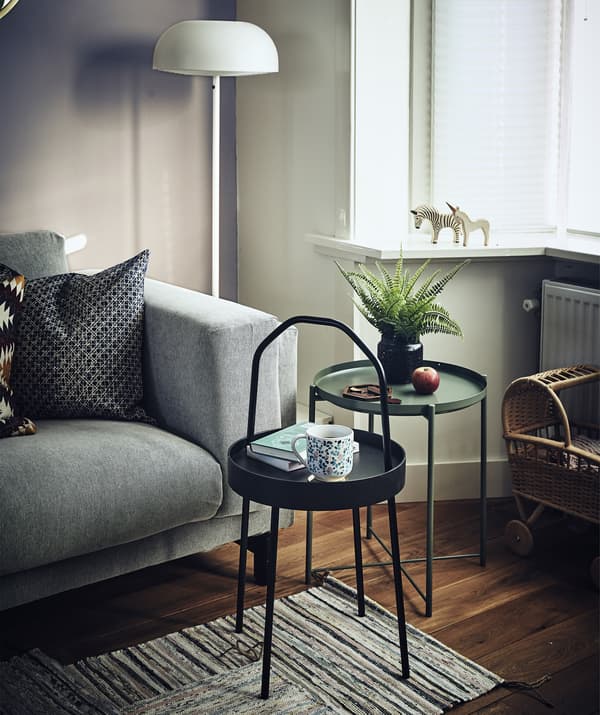 Two small, round side tables next to a sofa in a living room.