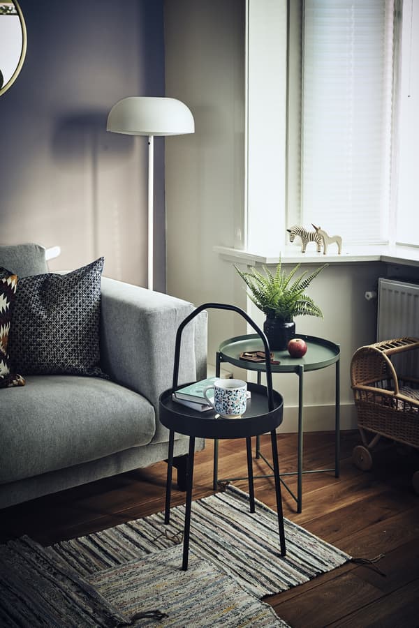 Two small, round side tables next to a sofa in a living room.