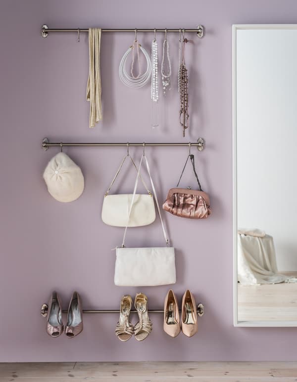 Two stainless steel rails, mounted to a violet wall to hold heels, purses, hats and jewellery.