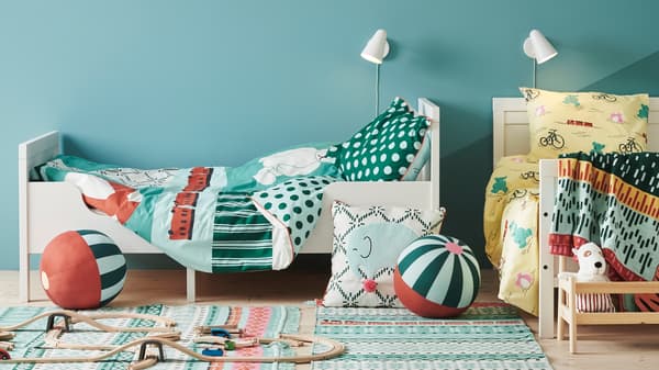 Two SUNDVIK beds with KÄPPHÄST quilt covers and pillowcases stand in a bedroom with a cushion and toys on the floor.