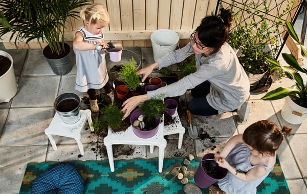 Two toddlers and a parent putting dirt into plant pots