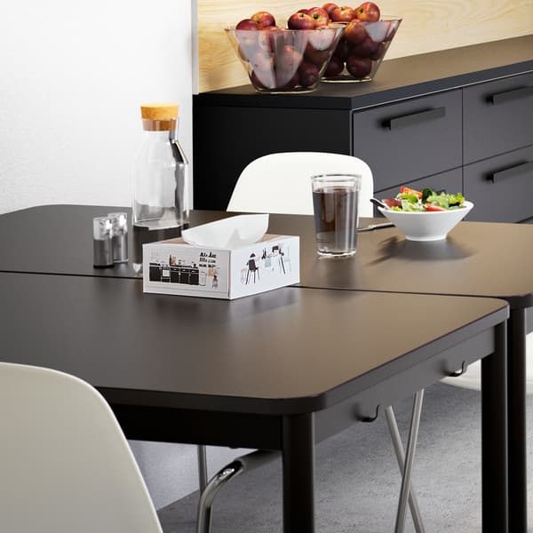 Two TOMMARYD tables in anthracite, two white chairs and bowls with lunch salad on top, standing in a kitchen.