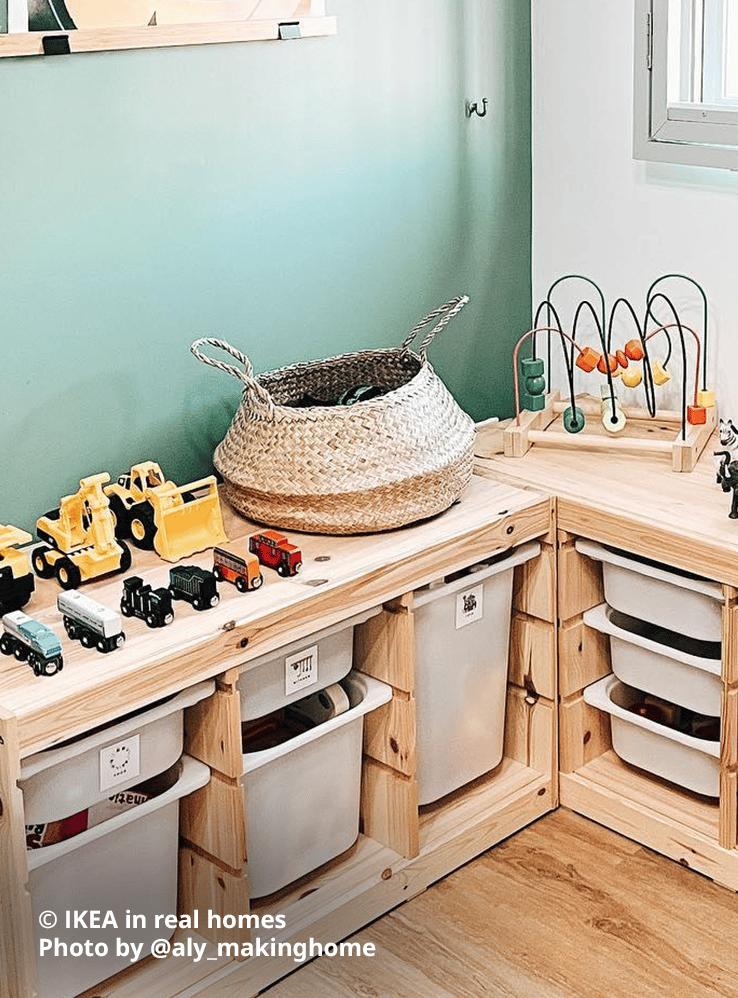Two TROFAST light white stained pine toy storage combinations in a corner of the home below a window with grills. Several toy trucks and cars, rattan basket and other toys are lined up on top of the storage combinations, with white TROFAST storage boxes in various sizes in each slot with toys. Photo by instagrammer @aly_makinghome for IKEA in real homes.
