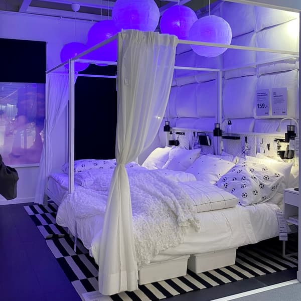 two VITARNA four-poster beds next to each other in a bedroom with a blue glow from the TRADFRI lamps.