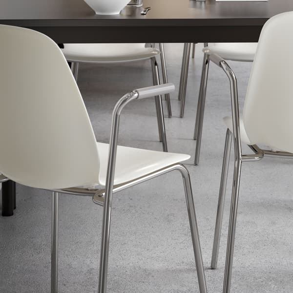 Two white chairs with armrests and the edge of an anthracite TOMMARYD table.