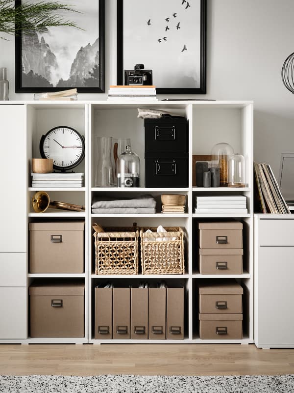 Two white VIHALS open shelving units side by side filled with storage boxes, baskets and other objects including a clock.