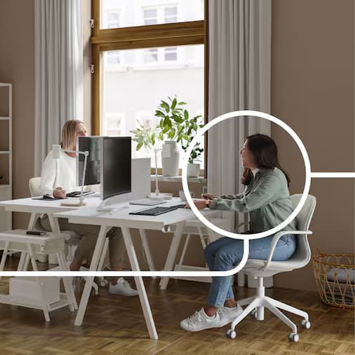 Two women are sitting at their desks in an office, working.