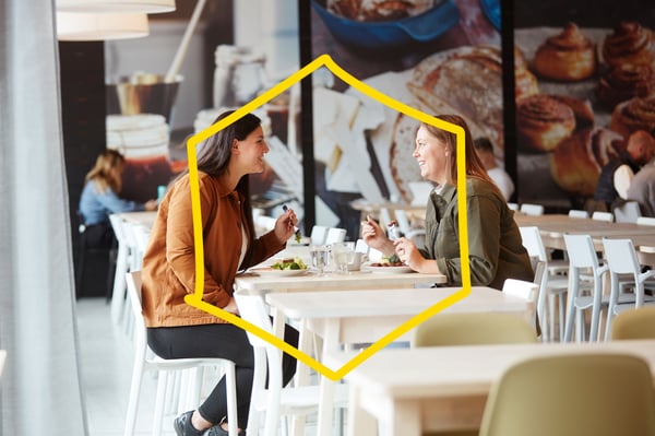 Two women are talking at a restaurant table.