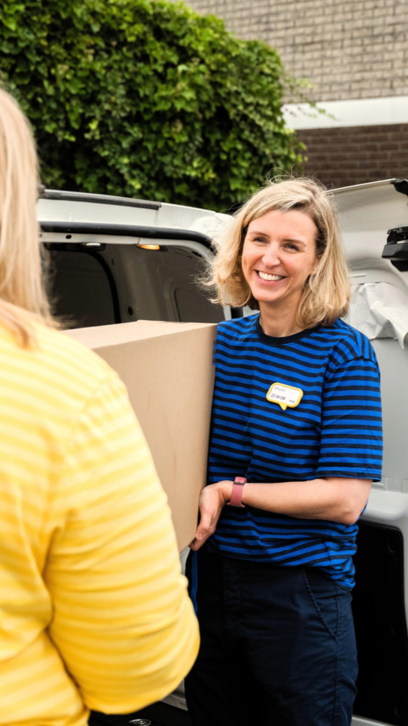 Two women holding a box out of a truck to deliver a customer