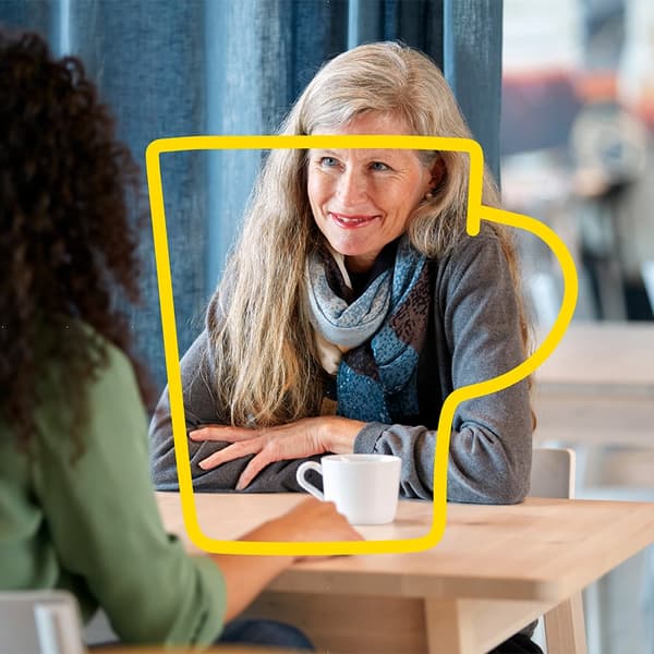 Two women in a café, surrounded by an IKEA illustration of a yellow coffee cup.