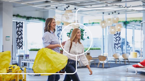 Two women with a yellow bag in an IKEA store.